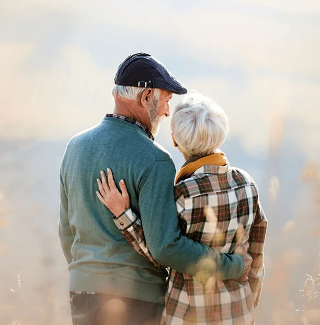 A senior couple standing together outdoors in warm afternoon light