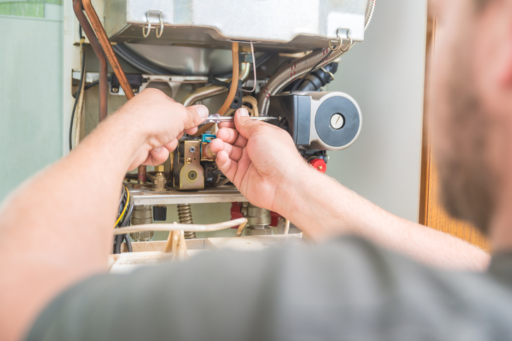 Heating Repair In Grass Valley, CA 1 A man repairs a gas boiler, focused on fixing its components.