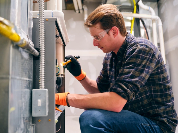 Furnace Repair in Truckee, CA 1 A man wearing a plaid shirt and safety glasses is repairing a furnace, demonstrating safety and skill.